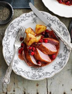 a white plate topped with meat covered in gravy and cranberry sauce