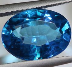 a blue oval shaped gems sits on a piece of leather in front of a white background