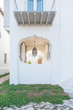 an open window in the side of a white building with steps leading up to it