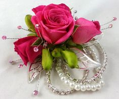 a pink rose and some pearls on a plate