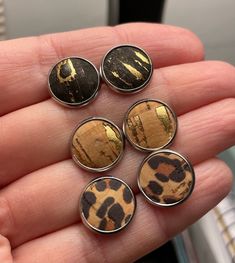 six leopard print buttons in the palm of someone's hand, with their fingers holding them