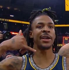 a man with dreadlocks standing in front of a basketball court and pointing to the side