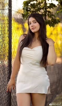 a woman posing in front of a fence