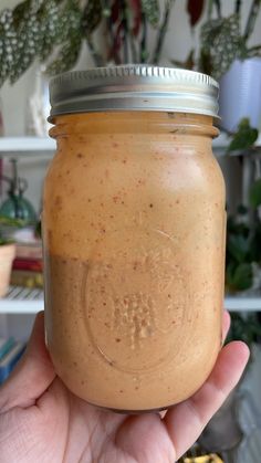 a hand holding a jar filled with peanut butter