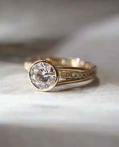 a close up view of a diamond ring on a white cloth with the background blurry