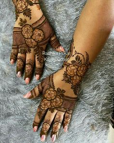 two hands with henna tattoos on them, one has flowers and the other has leaves