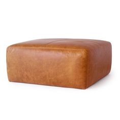 a brown leather ottoman sitting on top of a white floor