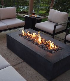 a fire pit sitting on top of a patio next to two couches and chairs