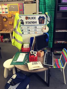 a desk with a laptop computer on top of it next to a police station sign