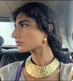 a woman in a car wearing a gold necklace