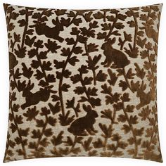 a brown and white pillow that has leaves on it with a bird in the middle