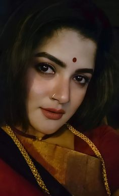 a close up of a person wearing a red shirt and gold necklace with a nose ring