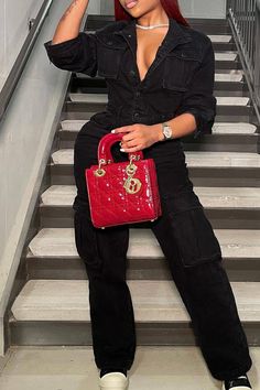 a woman with red hair is sitting on the stairs and holding a red handbag