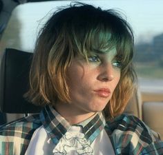 a woman sitting in the back seat of a car wearing a plaid shirt and tie