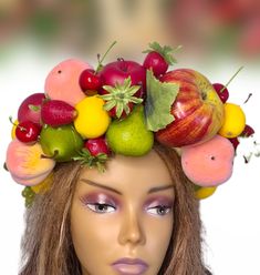 a mannequin with fruit on top of it's head, including apples, oranges and pears