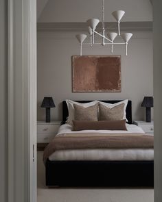 a bedroom with a bed, lamps and pictures on the wall