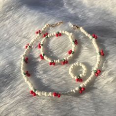 a white beaded necklace with red and green beads is on top of a pile of snow