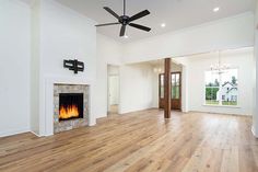 an empty living room with wood flooring and a fireplace in the center, surrounded by white walls