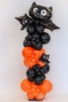 an orange and black balloon tower with bats on it's head is shown in front of a white background