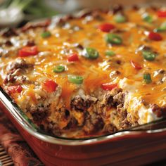 a casserole dish with meat, cheese and green peppers on it sitting on a place mat