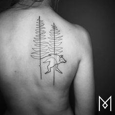 the back of a woman's shoulder with trees and a bear tattoo on it