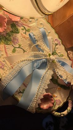 a decorative plate with blue ribbon and flowers on it