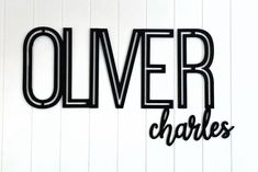 the word'olver charles'is cut out of black paper and placed on a white wall