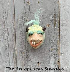 an odd looking mask hanging on the side of a wooden wall with text that reads, the art of lucky straddy