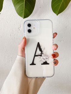 a woman holding up her phone case with the letter a on it