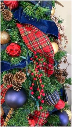 a christmas tree decorated with plaid and ornaments, including pine cones, blue ribbon, red berries