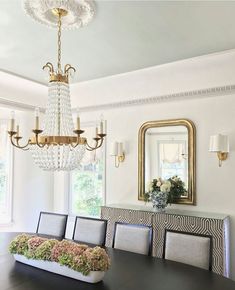 a chandelier hanging from the ceiling in a dining room with white walls and chairs