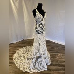 the back of a wedding dress on display in a room with white walls and wood flooring