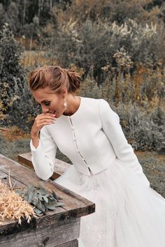 a woman in a white dress leaning on a wooden table