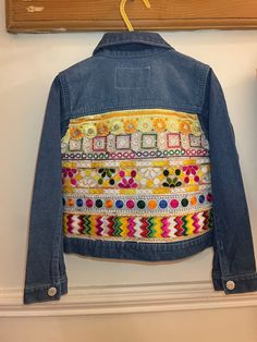 Mini Indie embroidered denim jackets are handmade by Esme in Manchester UK.  Age 4-5 years  Super soft stretch denim  Stone washed denim jacket with ruffle detail at front and center front button fastening. Embroidered back with gorgeous multicoloured Indian braid fabric.  EsmeAndTheEye upcycles second-hand denim jackets and gives them a new lease of life by adding beautiful Indian braid and embroidered textiles.  Each piece is hand picked by Esme and loving re-worked to create a hippie unique j Hippie Patchwork Denim Jacket For Spring, Spring Hippie Patchwork Denim Jacket, Spring Festival Denim Blue Outerwear, Bohemian Denim Blue Patchwork Outerwear, Multicolor Patchwork Cotton Denim Jacket, Festival Denim Patchwork Outerwear, Bohemian Denim Outerwear With Multicolor Embroidery, Multicolor Cotton Patchwork Denim Jacket, Multicolor Patched Denim Jacket For Spring