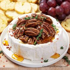 a cheese dish with pecans, grapes and crackers on the side for garnish