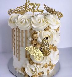 a birthday cake with white frosting and gold decorations on it's side, decorated with butterflies