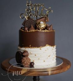 a birthday cake is decorated with chocolate and gold decorations