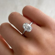 a woman's hand with a diamond ring on top of her finger, showing the center stone