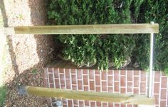 there is a wooden rail on the side of a brick wall next to some bushes