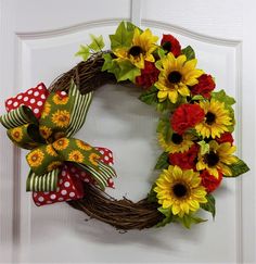 a wreath with sunflowers and polka dot bows hangs on the front door's white door