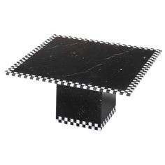 a black and white square table with checkered design on the top, sitting in front of a white background