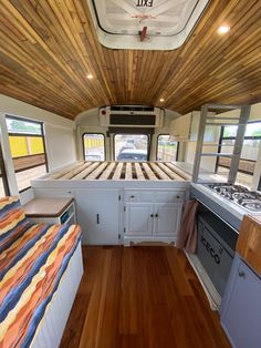 the interior of an rv with wood flooring and white cabinets, including a stove top oven