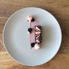 a piece of chocolate cake on a white plate with strawberries and whipped cream topping