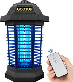 a person holding a remote control next to a blue light tower with the word gootop on it