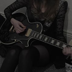 a woman sitting on the floor playing an electric guitar