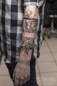 a man with a flower tattoo on his arm and wrist is standing in front of a tile floor