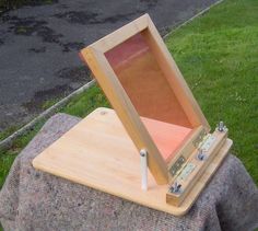 an open wooden box sitting on top of a rock next to a grass covered field