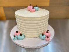 there is a white cake with pink and blue frosting on the top, sitting on a plate