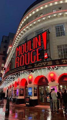 people are standing in front of the mouniin rouege theater at night