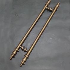 two antique brass candlesticks sitting side by side on a gray surface with one candle in the middle